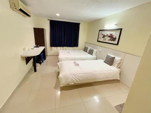a hotel room with two beds and a sink at Happiness Hotel in Kulai