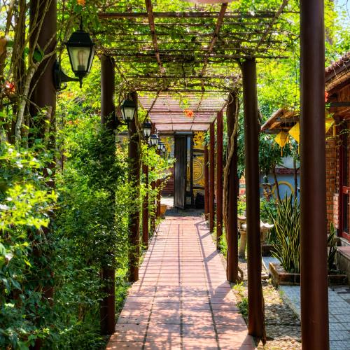 a walkway in a garden with a pergola at Vũ Di Homestay in Hue