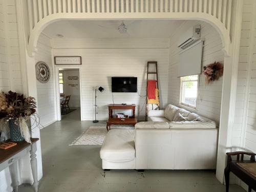 a living room with a white couch and a tv at Oakmore Cottage Charming Old Vintage Queenslander - Central location in Bundaberg