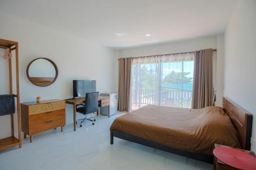 a bedroom with a bed and a desk and a window at First light beach hin kong in Hinkong