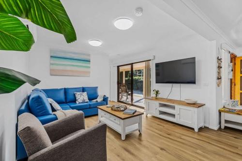 a living room with a blue couch and a tv at Winnies on Sunpatch in Tomakin