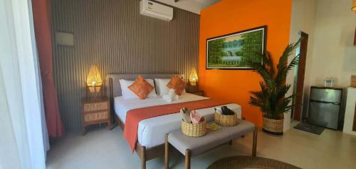 a bedroom with a bed with orange walls and a tv at lala-Oh Resort in Lalao