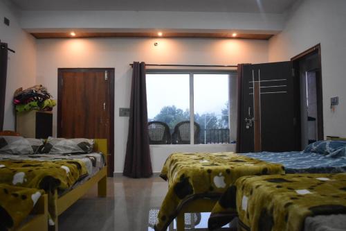 two beds are in a room with a window at Naisarga hill view homestay in Somvārpet