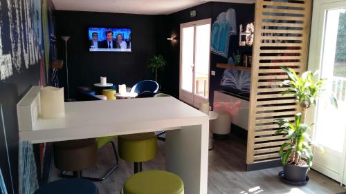 a room with a desk and stools and a tv on the wall at Ibis Budget Agen in Le Passage