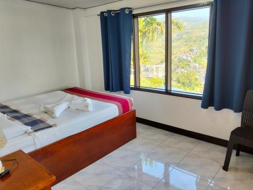 a bedroom with a bed and a large window at The Verandah Lodge Bed and breakfast in Banaue