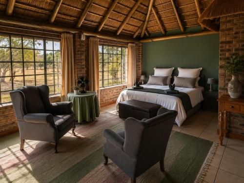 a bedroom with a bed and two chairs in a room at Roaring Sky Base Camp in Cullinan