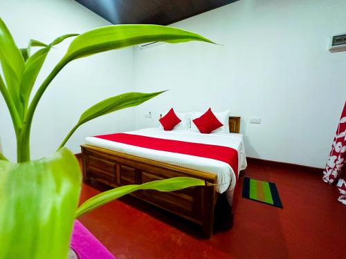 a bedroom with a bed with red pillows and a plant at Sigiri Grand Villa in Sigiriya