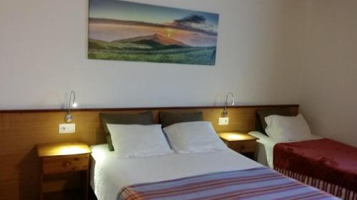 a bedroom with two beds and a painting on the wall at Hospetur 2 in Horta