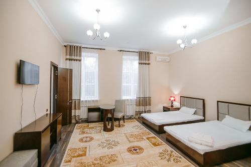 a bedroom with two beds and a flat screen tv at Hotel Inju in Taraz