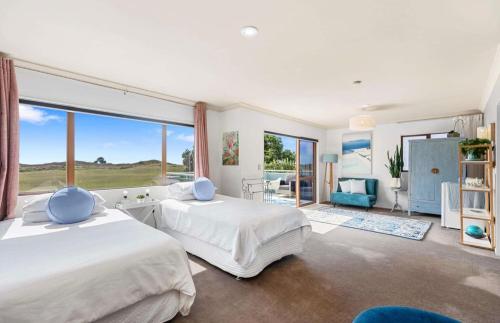 a bedroom with two beds and a large window at Beach Apartment in Papamoa