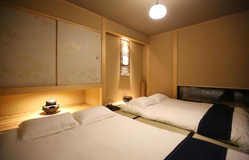 a room with two beds and a lamp in it at Machiya Minami Omiya in Kyoto