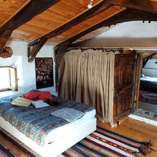 a bedroom with a bed in a room with wooden ceilings at Charensol in Saint-Sauveur-de-Montagut