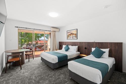a hotel room with two beds and a table at Sundowner Hotel Motel in Caboolture