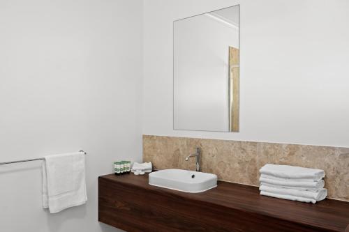 a bathroom with a sink and a mirror and towels at Sundowner Hotel Motel in Caboolture