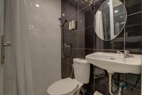a bathroom with a toilet and a sink and a mirror at Hotel Bunga-Bunga By ARBA in Jakarta