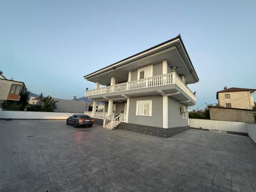 a house with a car parked in a parking lot at Vila Muhadri in Kamëz