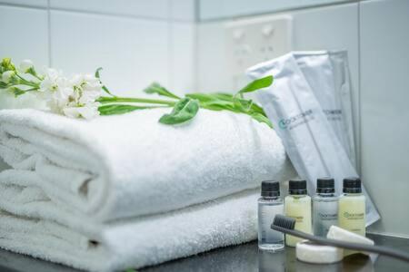 a pile of towels and cosmetics on a bathroom counter at Clocktower Apartment Hotel in Melbourne