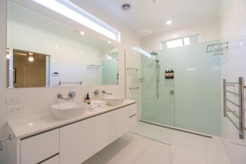 a white bathroom with two sinks and a shower at Wandew - Echuca Holiday Homes in Echuca