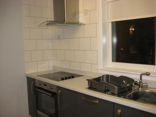 a kitchen with a stove and a sink and a window at Da Milk Shop Holiday Home in Scalloway