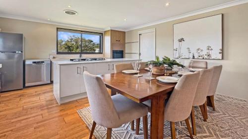 a kitchen and dining room with a wooden table and chairs at Watersedge in Currarong