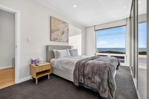 a bedroom with a bed and a large window at Sunset Sands on Esplanade By Host Solutions in West Beach