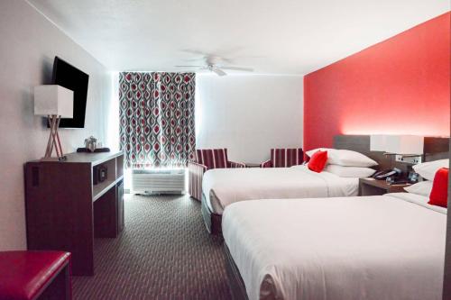 a hotel room with two beds and a red wall at Radisson Hotel Orlando Lake Buena Vista South in Kissimmee