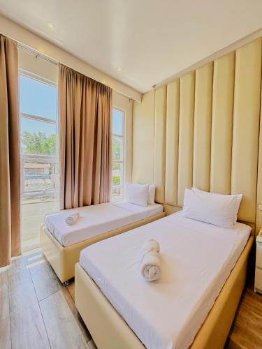 two beds in a room with a window at Pitstop Mango Grove Retreat in Guimaras