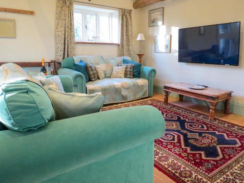 a living room with a couch and a tv at Appletree Cottage Fressingfield in Fressingfield