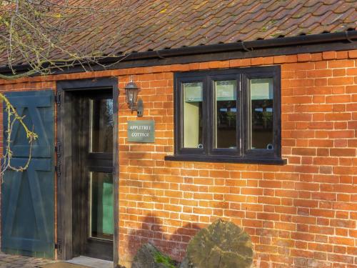 a brick building with a blue door and windows at Appletree Cottage Fressingfield in Fressingfield