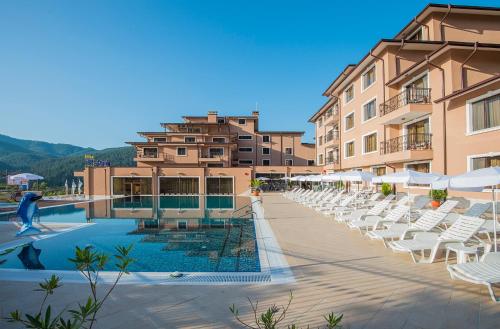 a resort with a swimming pool with white lounge chairs at Park Hotel and SPA Vella Hills in Velingrad