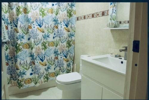 a bathroom with a shower curtain with a toilet and a sink at Confortable in San Isidro