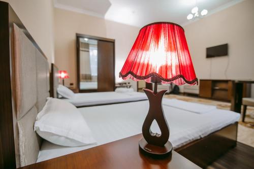 a bedroom with a bed and a red lamp on a table at Hotel Inju in Taraz