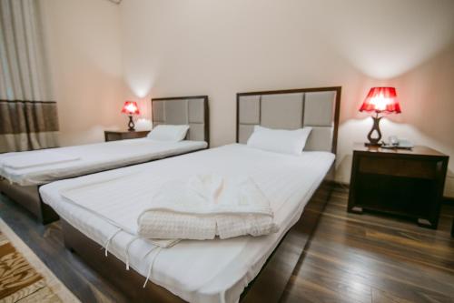 two beds in a room with two lamps on tables at Hotel Inju in Taraz
