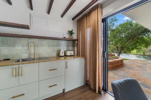 a kitchen with white cabinets and a sliding glass door at Lakes Edge Retreat in Yungaburra