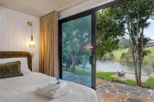a bedroom with a large window with a view of a lake at Lakes Edge Retreat in Yungaburra