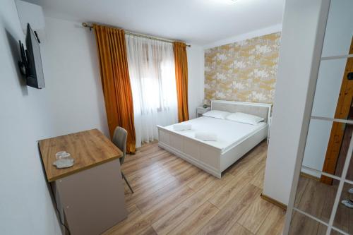 a small bedroom with a bed and a desk at ELITEO GUESTHOUSE Dabuleni in Dăbuleni