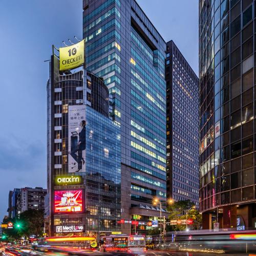 a tall building with a sign on it in a city at CHECK inn Taipei Xinyi in Taipei
