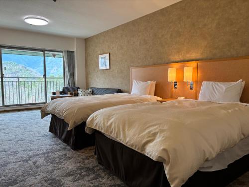 a hotel room with two beds and a large window at Fuji View Hotel in Fujikawaguchiko