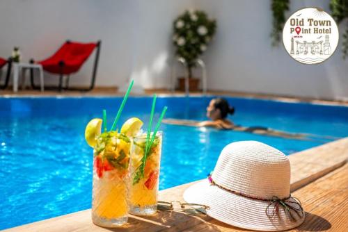 a hat and a drink on a table next to a swimming pool at Old Town Point Hotel & Spa Antalya in Antalya