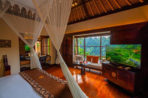 a bedroom with a bed and a flat screen tv at Hanging Gardens of Bali in Payangan