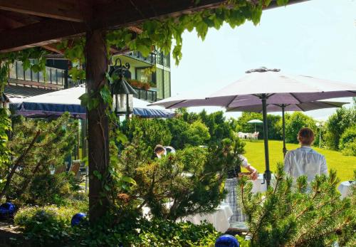 a group of people walking around a garden with an umbrella at Mittelburg Wellnesshotel in Oy-Mittelberg
