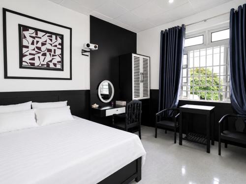 a black and white bedroom with a bed and a desk at The Luxe Homestay in Buôn Ðũng