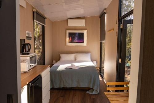 a small bedroom with a bed and a microwave at Black Snake Sky Box by Tiny Away in Grantow