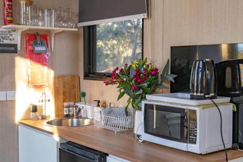 a kitchen counter with a microwave and a sink at Black Snake Sky Box by Tiny Away in Grantow