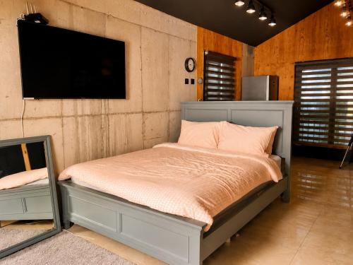 ein Schlafzimmer mit Bett und Flachbildfernseher in der Unterkunft 수스테이 펜션 in Seogwipo