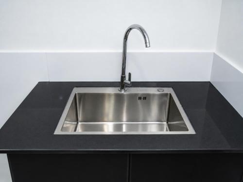 a stainless steel sink in a black counter top at The Luxe Homestay in Buôn Ðũng