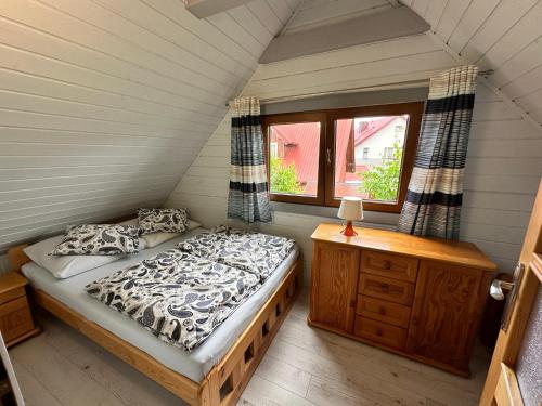 a bedroom with a bed and a dresser and a window at AchKaszuby domki nad morzem in Puck