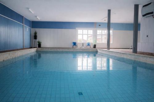 a large swimming pool with two blue chairs in it at Rudbøl Naturcamping in Højer