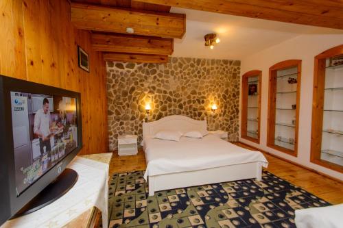 ein Schlafzimmer mit Bett und Flachbildfernseher in der Unterkunft Rem's Pension in Râșnov