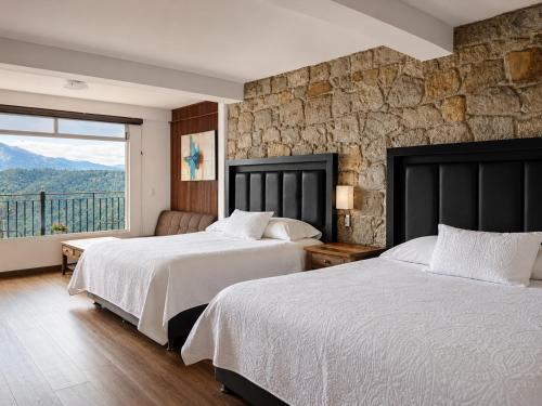 two beds in a room with a stone wall at Vista Zacatlan Hotel in Zacatlán